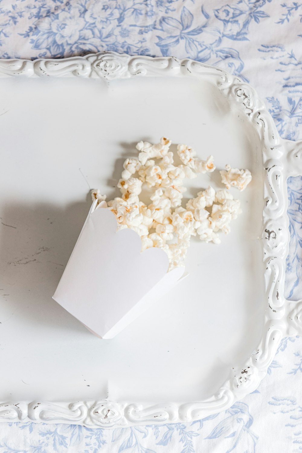 a white tray topped with a white container of popcorn
