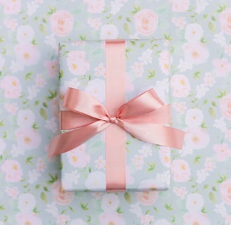 a present wrapped in pink ribbon on a floral background