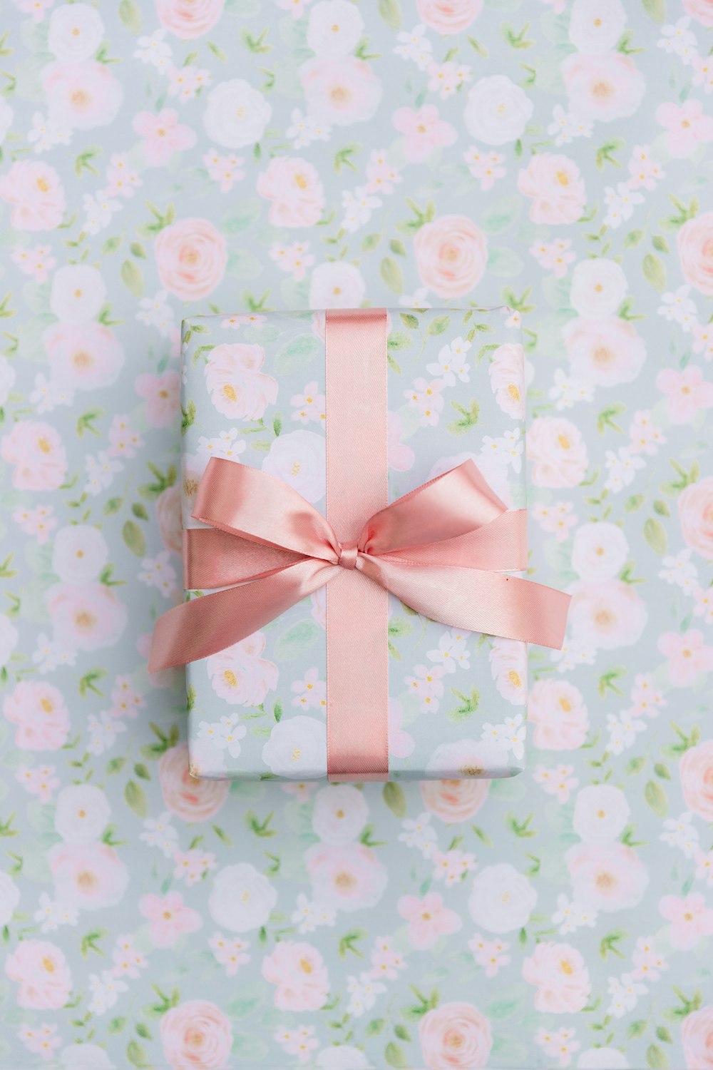 a present wrapped in pink ribbon on a floral background