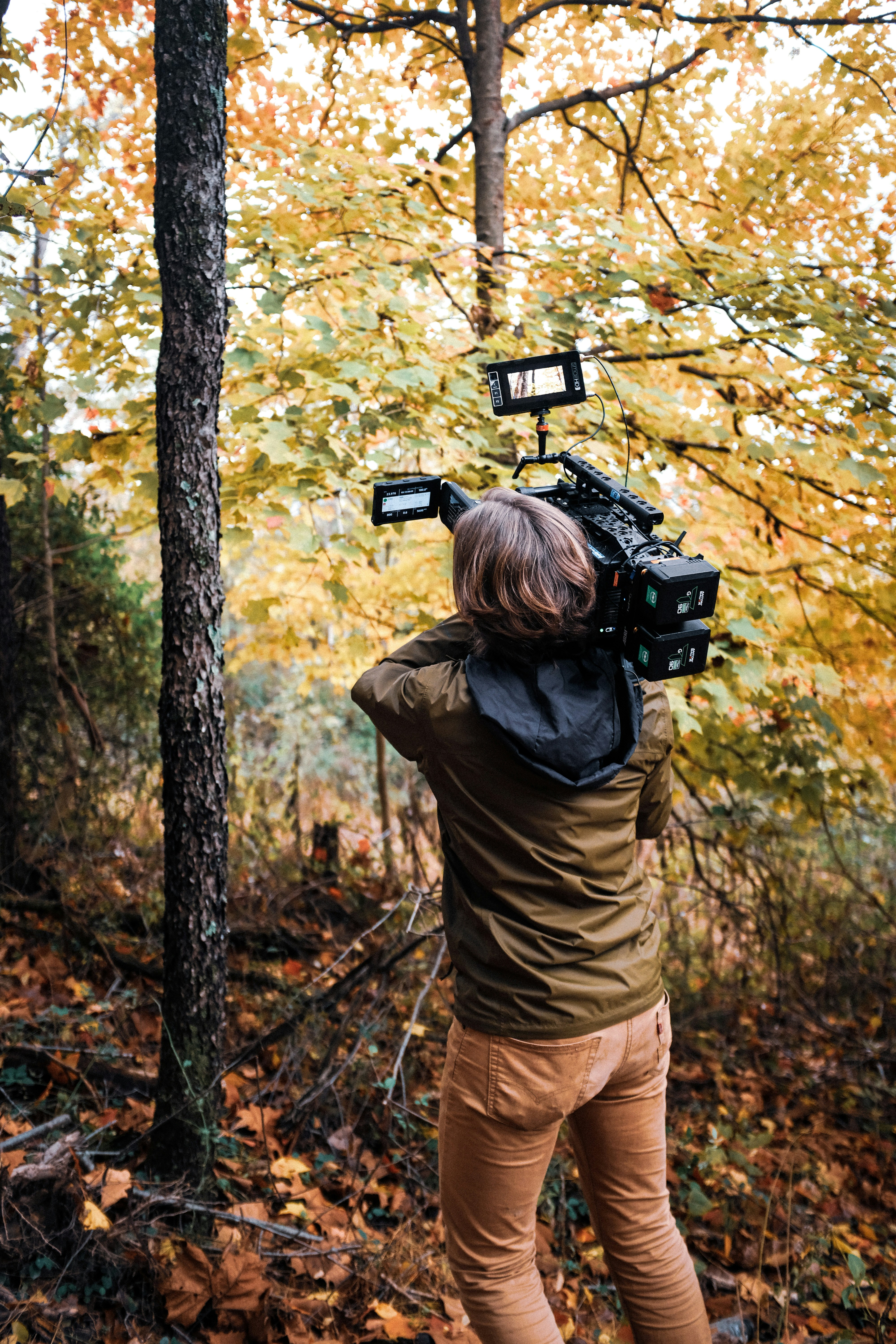 eine Person, die mit einer Kamera im Wald steht
