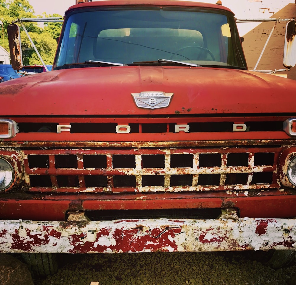 an old red ford truck parked in a yard