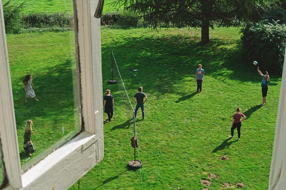 a group of people standing on top of a lush green field