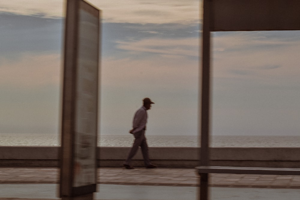 a man walking down a sidewalk next to the ocean