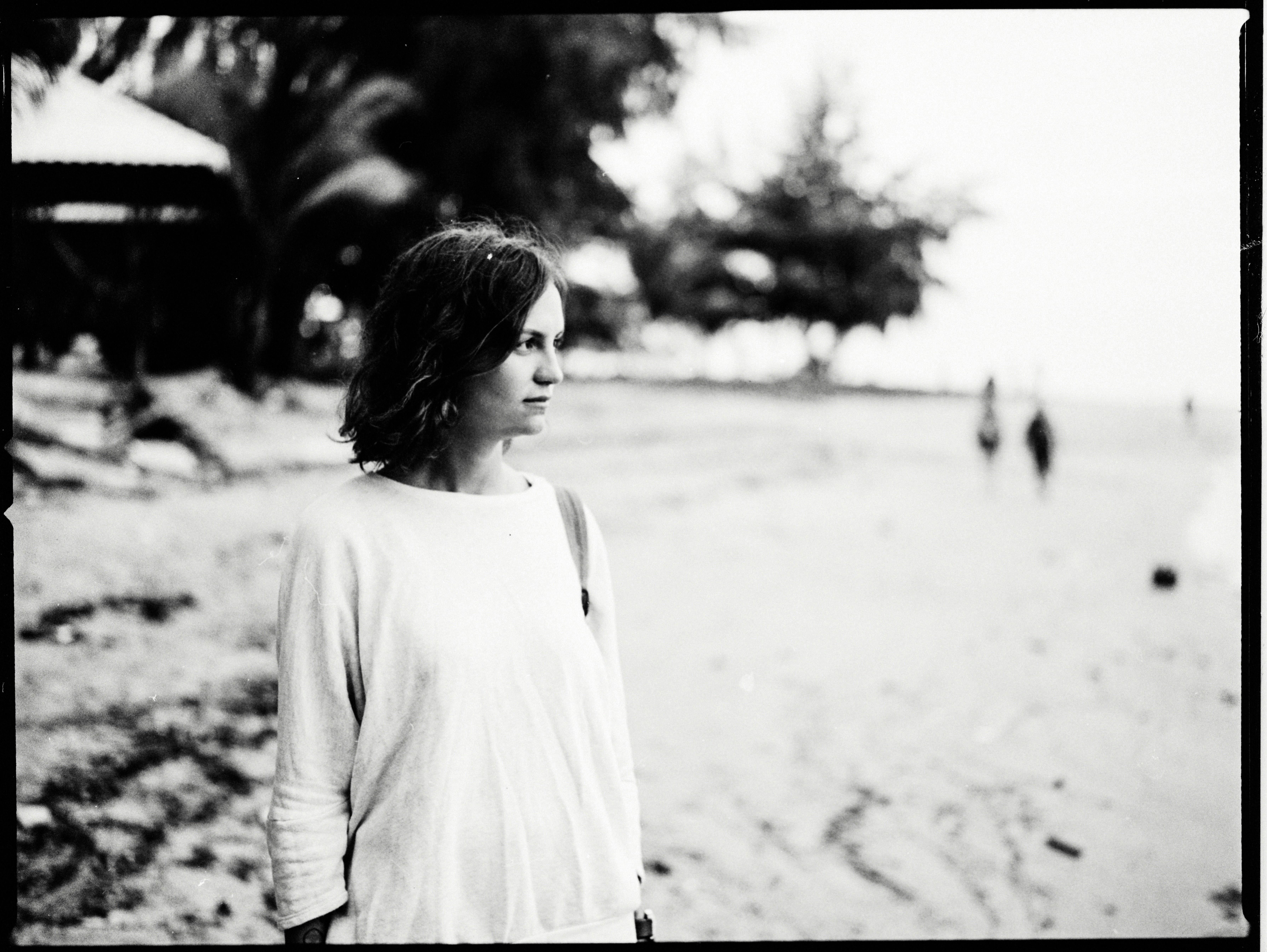 A black and white photo of a woman standing on a beach photo – Free ...