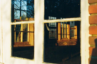 Close-up of a residential window with a freshly applied reflective insulfilm under natural sunlight.