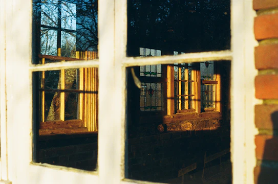 Close-up of a residential window with a freshly applied reflective insulfilm under natural sunlight.
