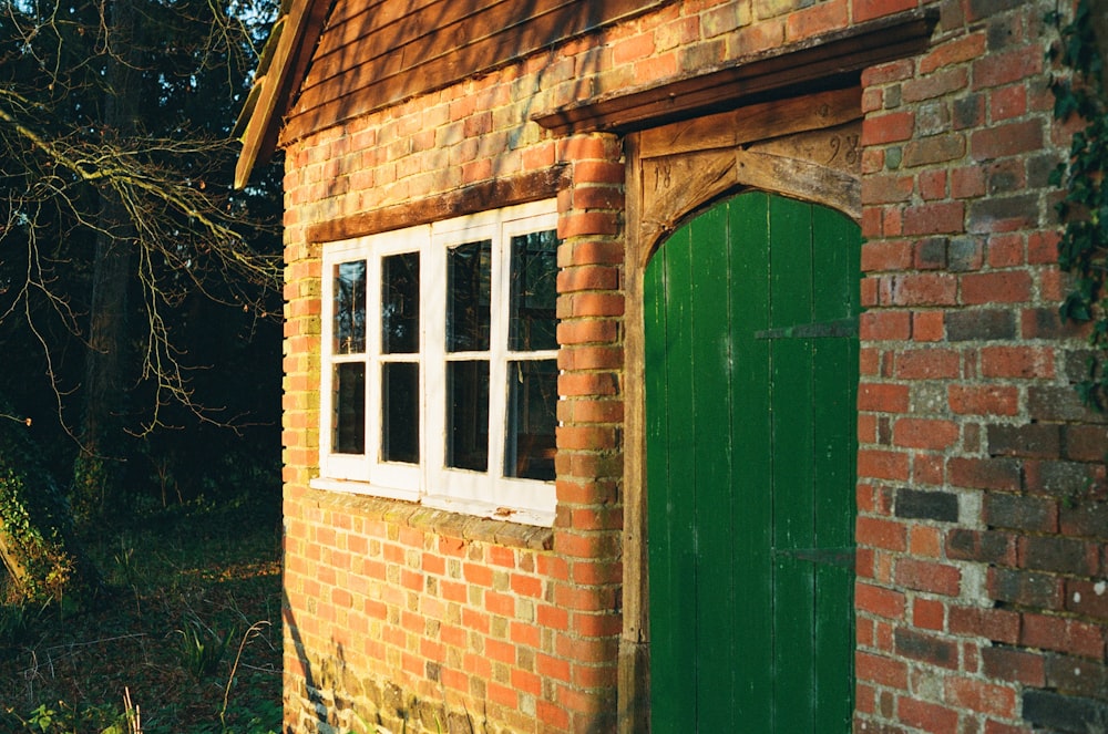 a brick building with a green door and window