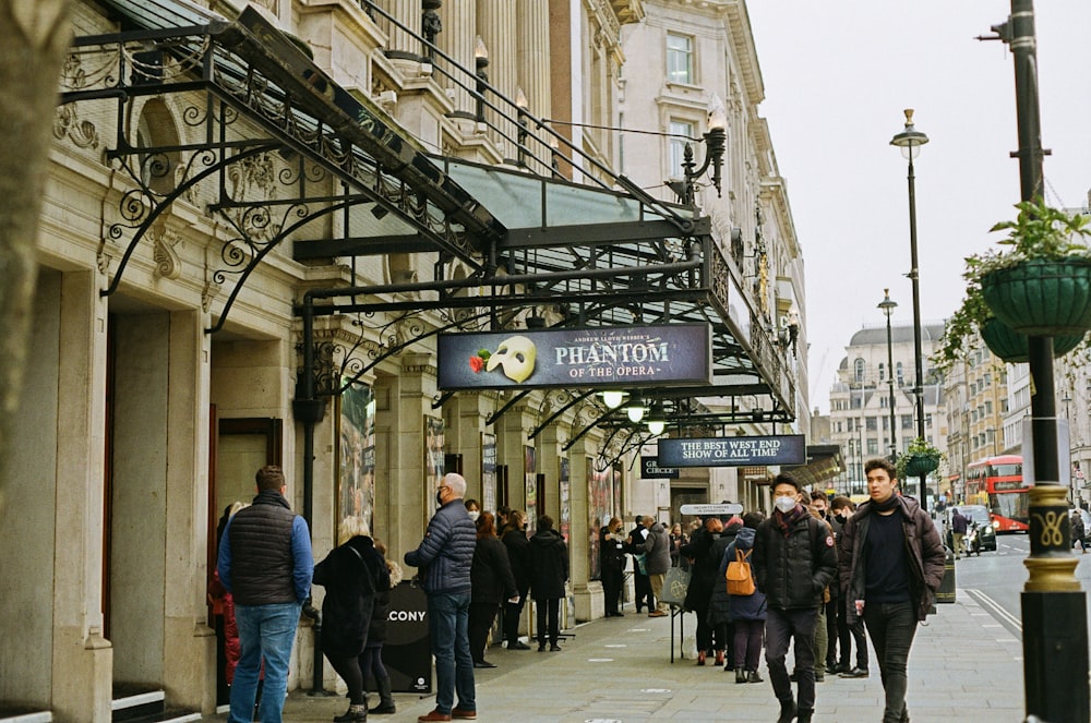 a group of people walking down a street next to tall buildings