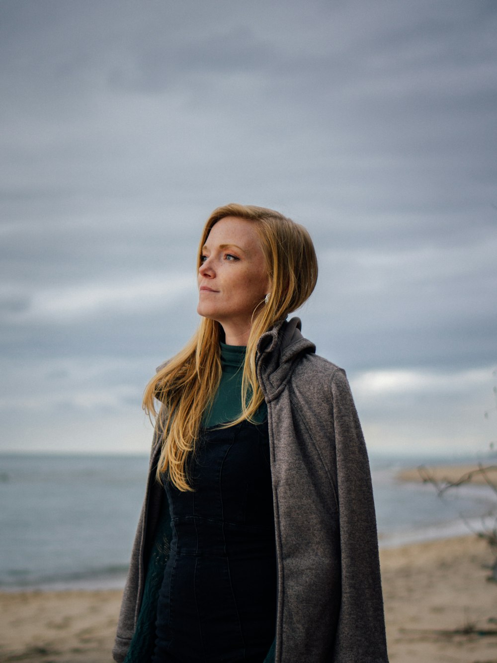 a woman standing on a beach looking up at the sky