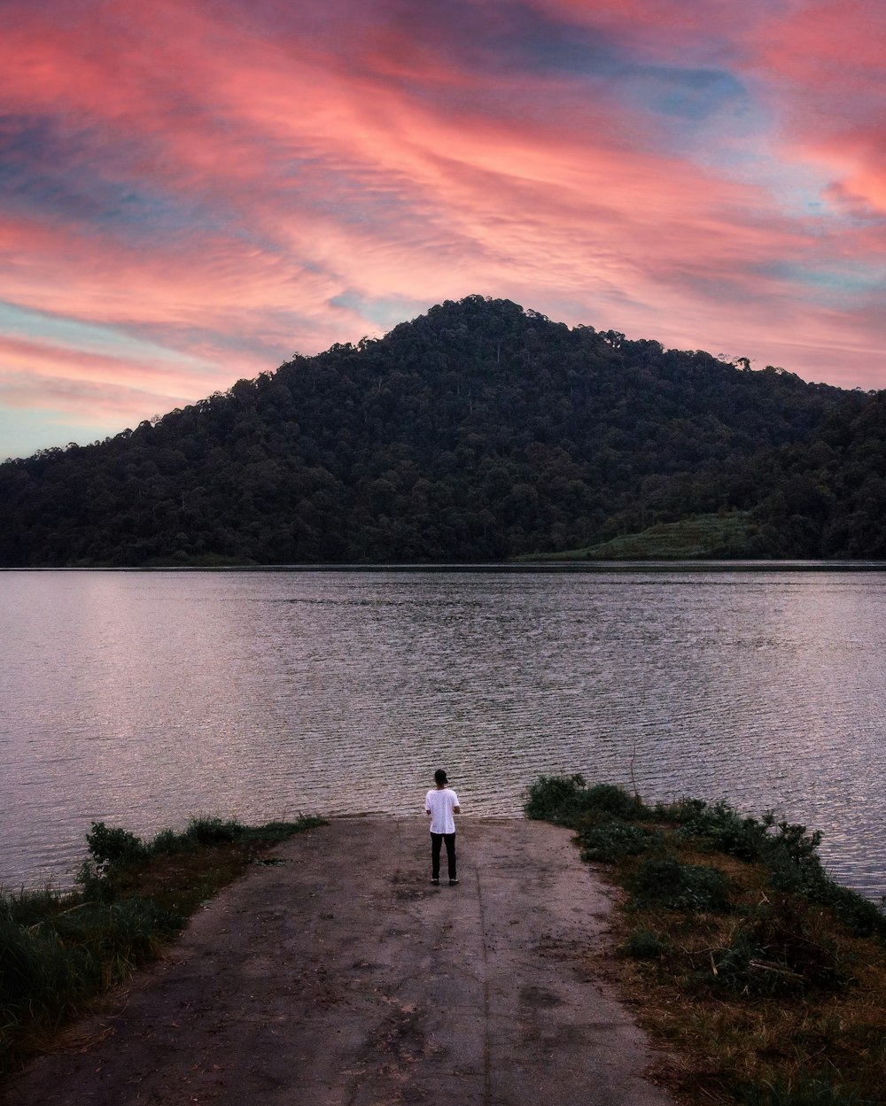a person standing on a path next to a body of water