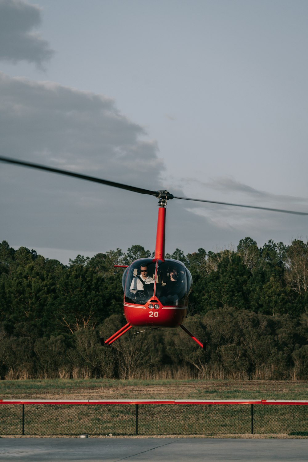 a red helicopter flying over a lush green forest