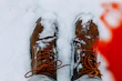 a person standing in the snow wearing brown boots