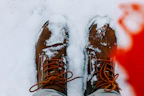 a person standing in the snow wearing brown boots