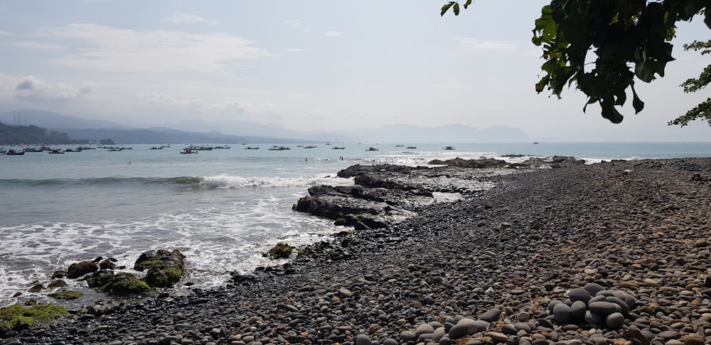 a rocky beach with boats in the water