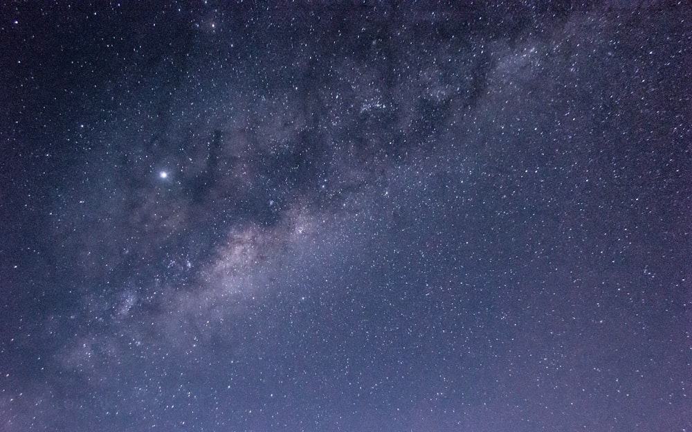 a group of people standing on top of a hill under a night sky filled with