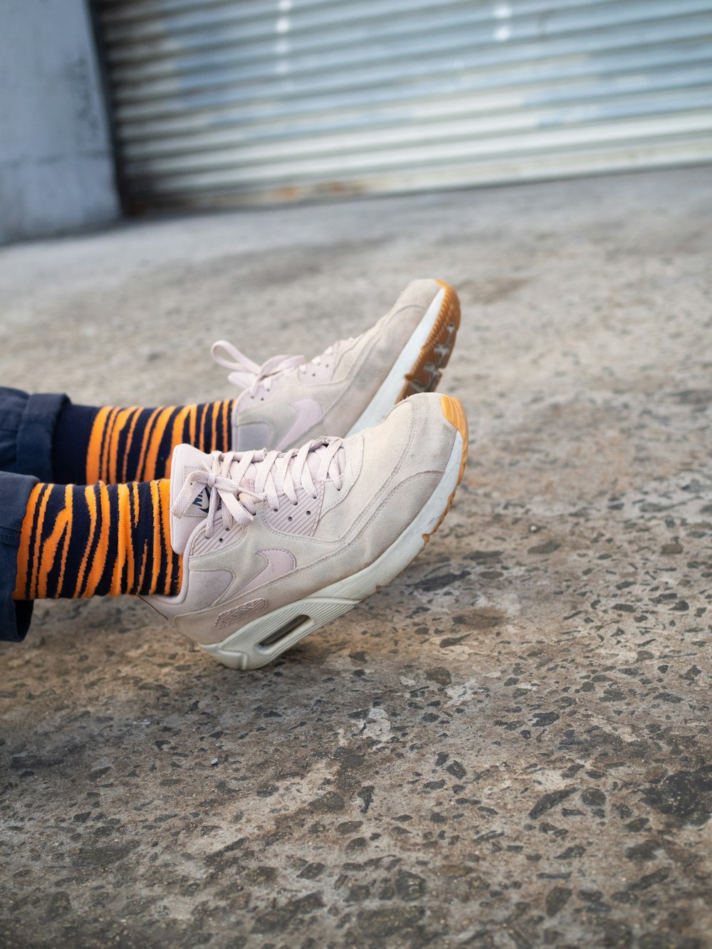 a pair of white sneakers with orange and black striped socks