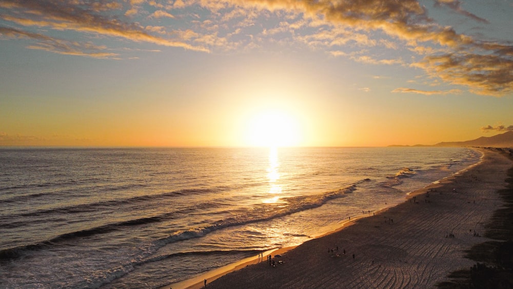 the sun is setting over the ocean on the beach