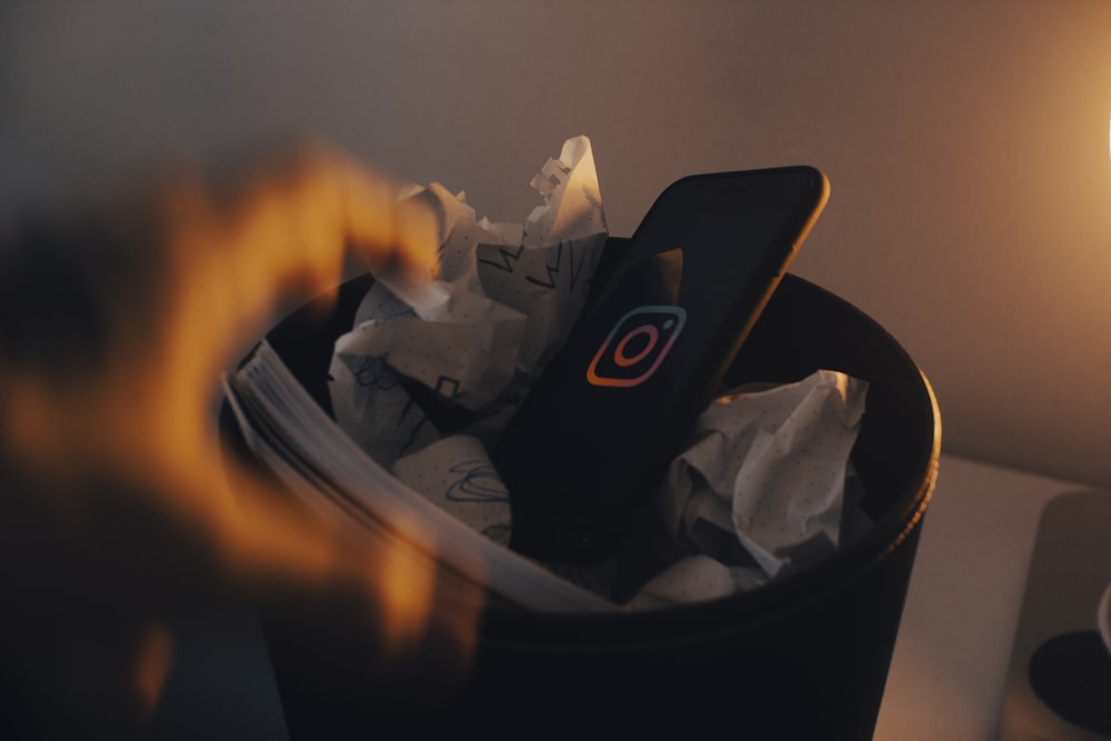 a trash can filled with paper and a cell phone