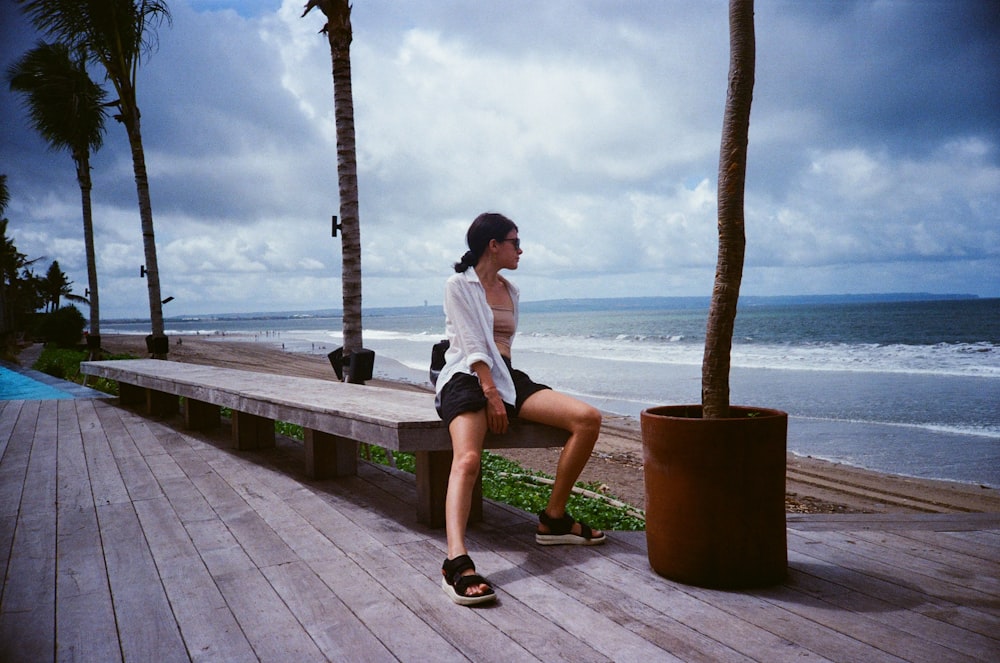 a woman sitting on a bench near the ocean