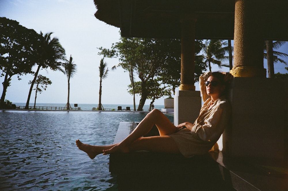 a woman sitting on the edge of a swimming pool