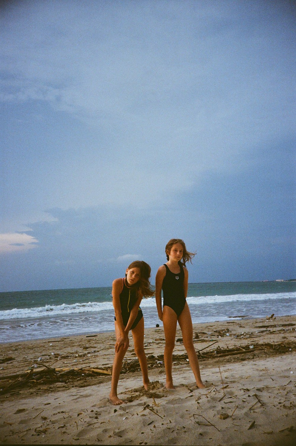 a couple of women standing on top of a sandy beach