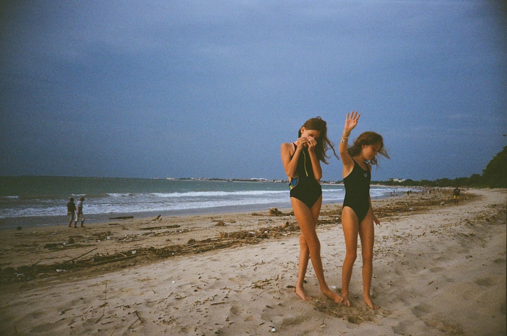 two girls in bathing suits standing on a beach