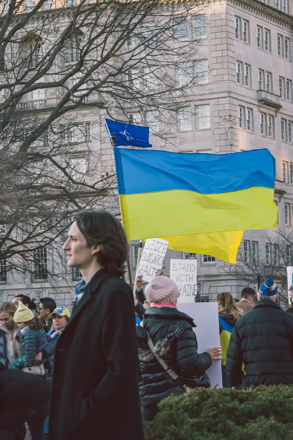 a woman holding a ukraine flag and a sign