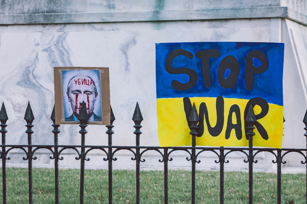광대 그림이 있는 울타리와 전쟁을 멈추라는 표지판
