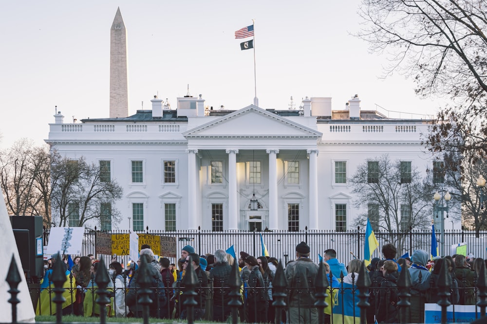 a group of people standing in front of a white house
