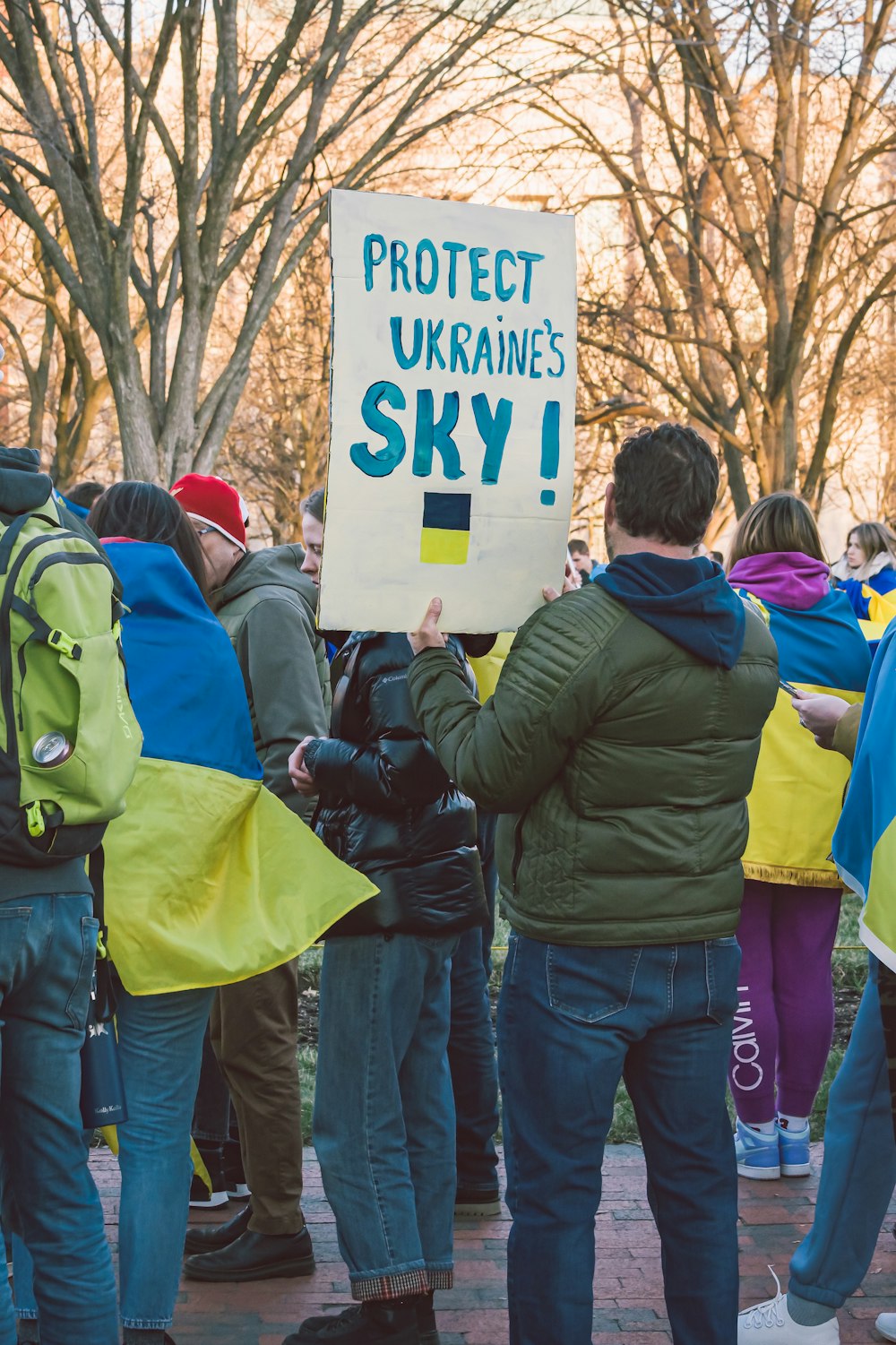 Un gruppo di persone con un cartello che dice Proteggi il cielo dell'Ucraina