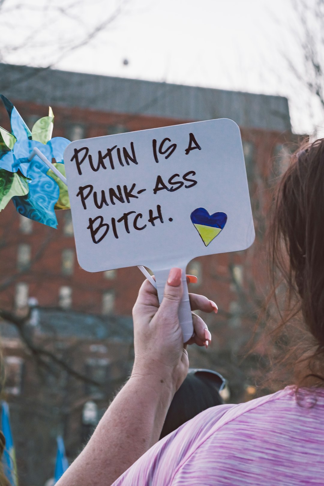 a woman holding a sign that says purin is a punk ass bitch