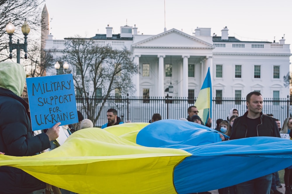 Un gruppo di persone che reggono cartelli davanti a una Casa Bianca