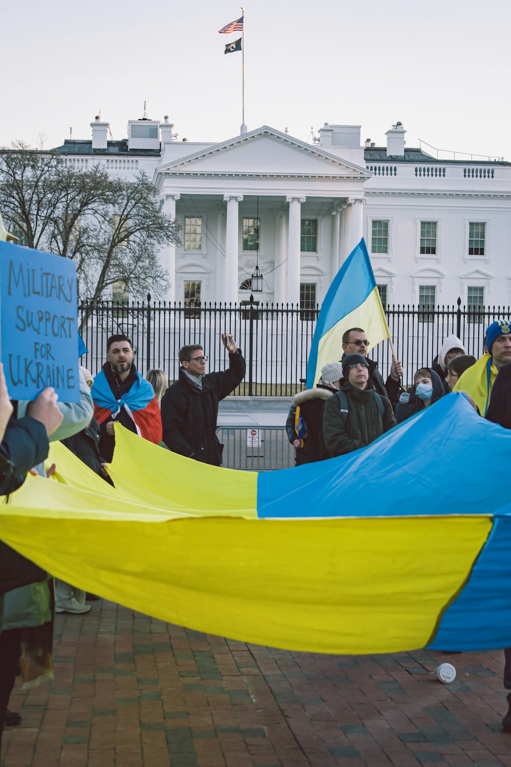 a group of people holding a large blue and yellow kite