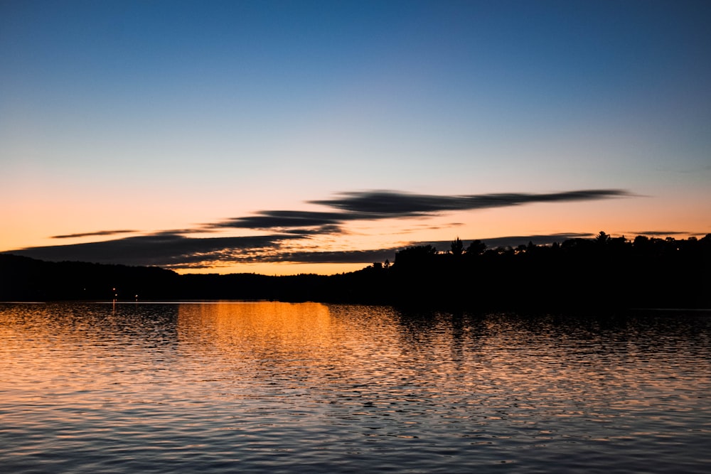 a body of water with a sunset in the background