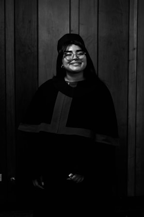 A graduate smiling proudly in cap and gown against a bright, clean background.