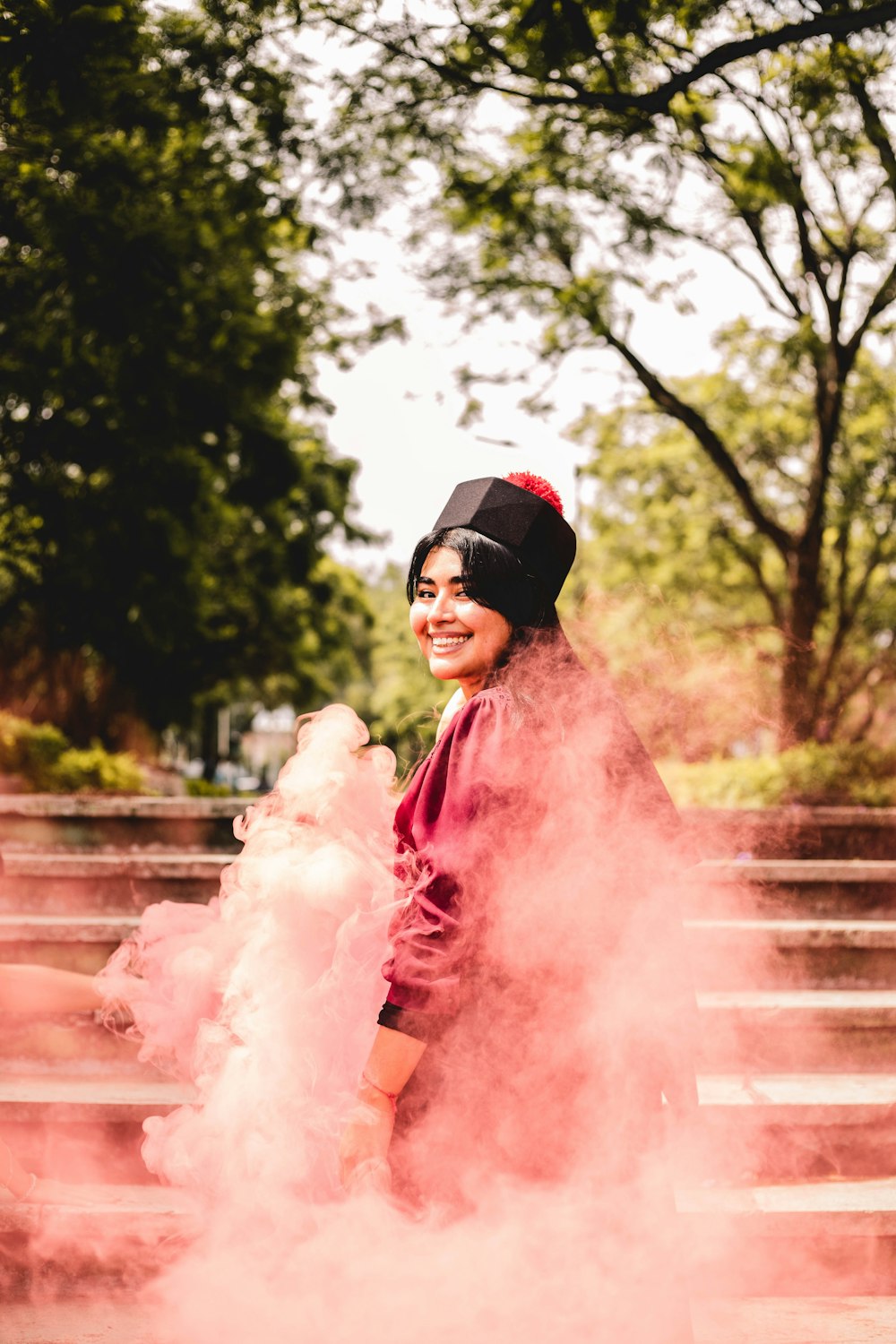 Una mujer parada frente a una nube rosa de humo