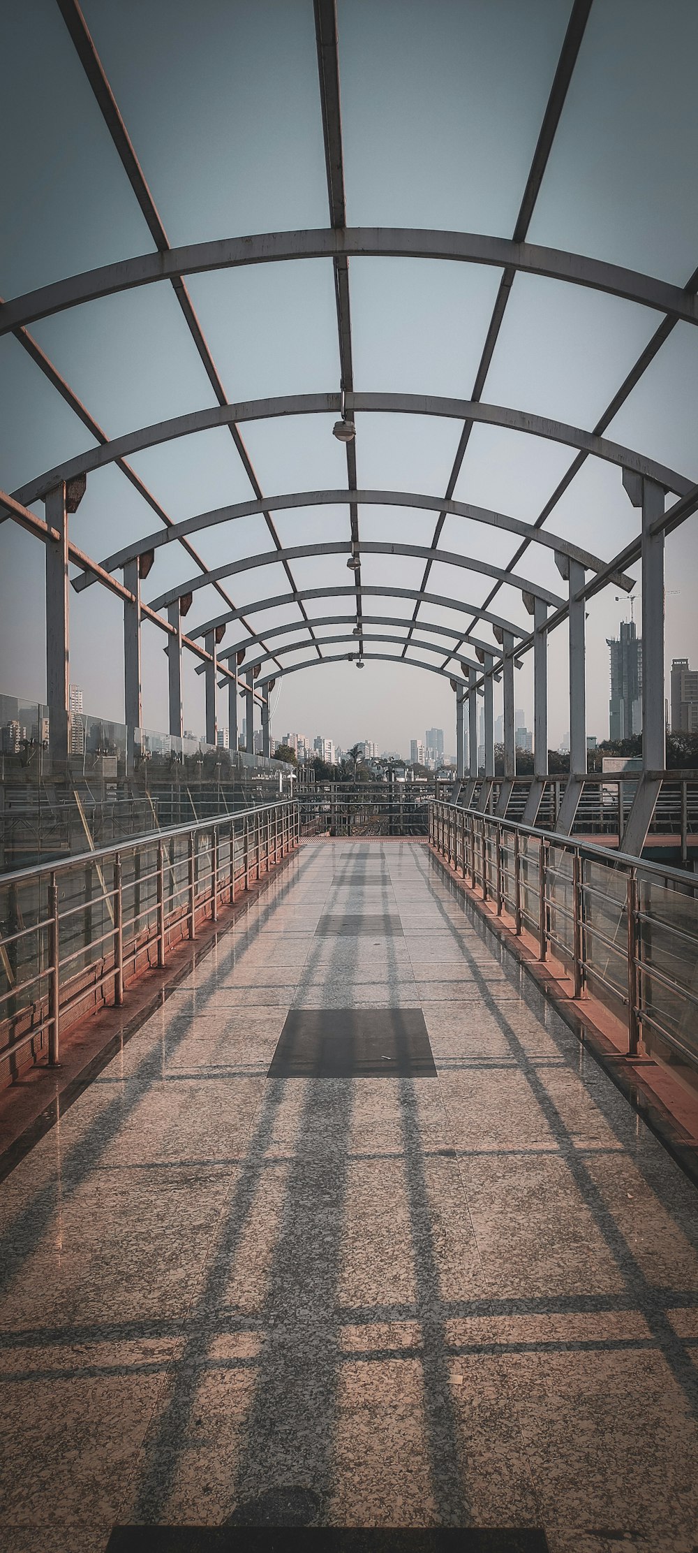 a long walkway with metal railings and a city in the background