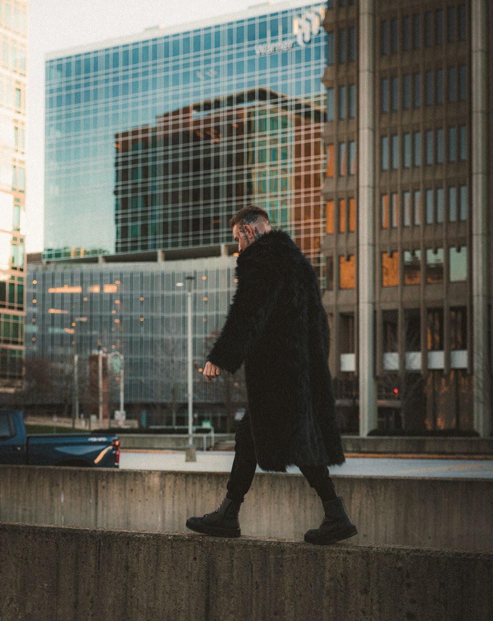 a man in a black coat walking down a sidewalk