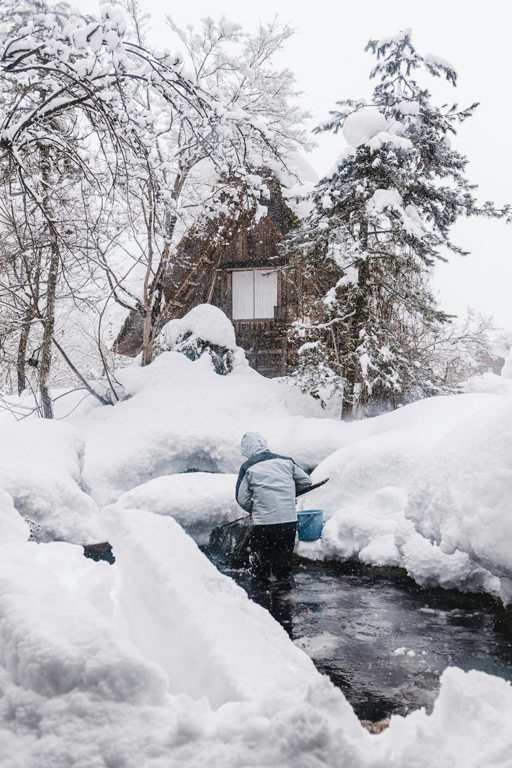 a person standing in a stream surrounded by snow