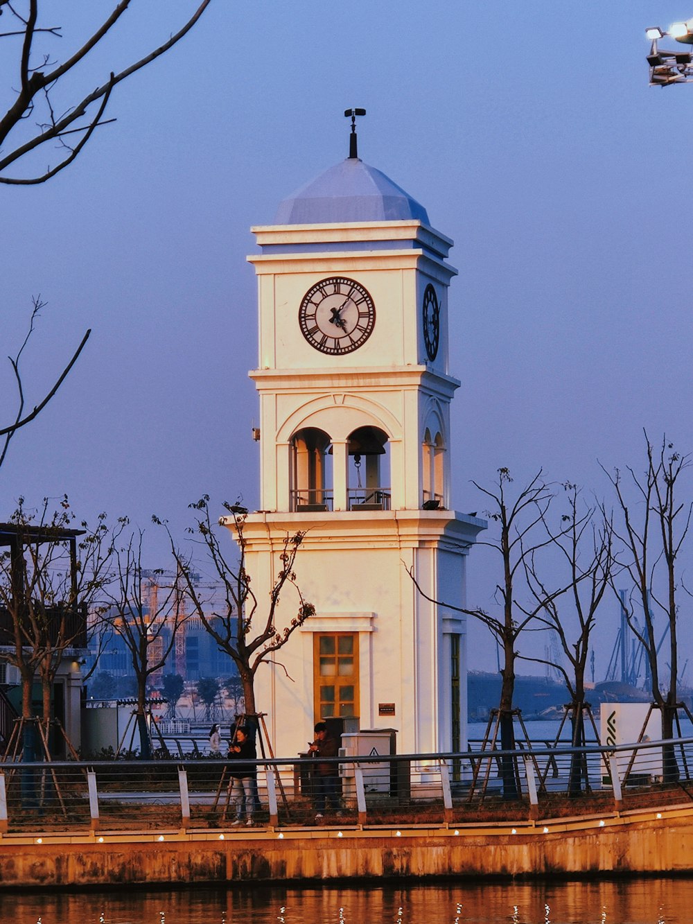 a white clock tower sitting next to a body of water