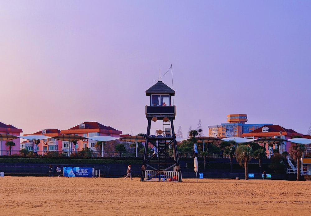 a lifeguard tower on a sandy beach with houses in the background