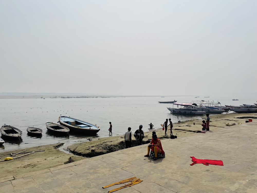 a group of people standing on a beach next to a body of water