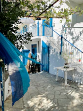 A sunlit courtyard with vibrant blue walls and lush greenery, set for an intimate wedding ceremony.