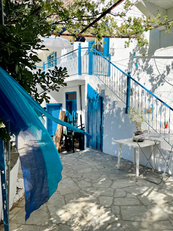A sunlit courtyard with vibrant blue walls and lush greenery, set for an intimate wedding ceremony.