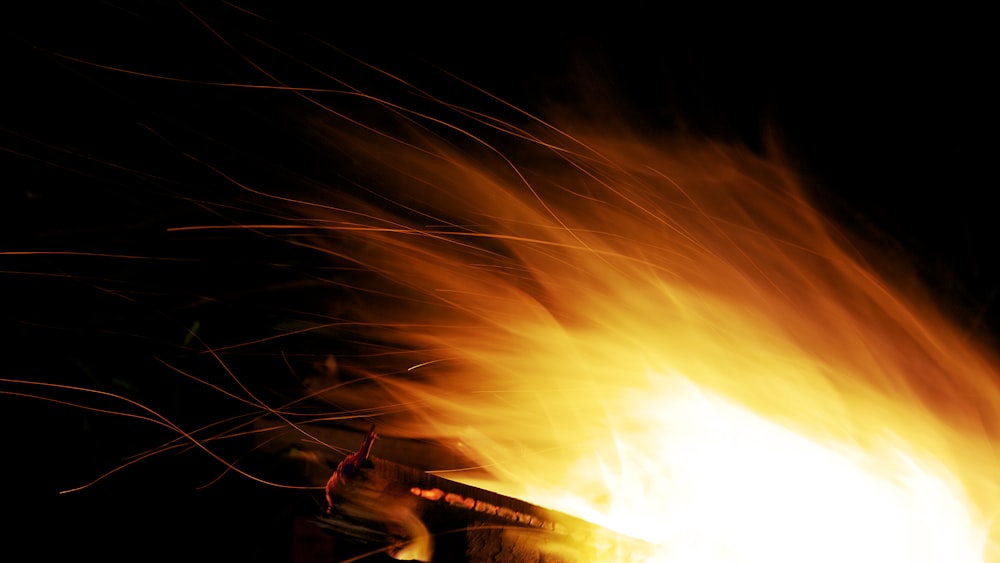 a person holding a lit object in front of a fire