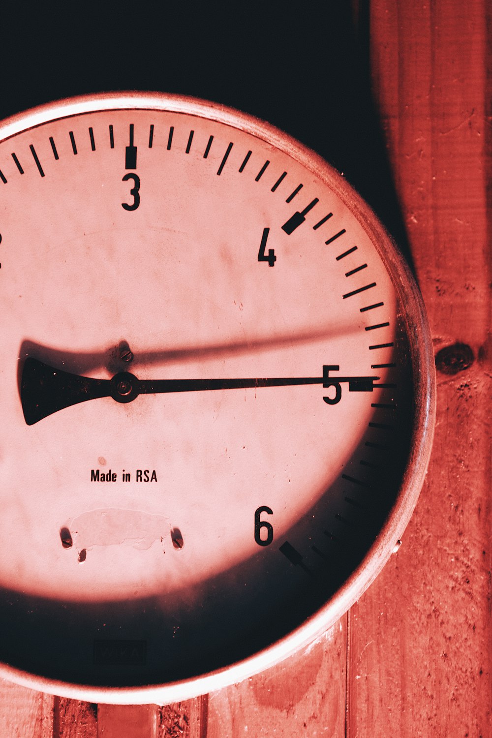 a close up of a clock on a wooden surface