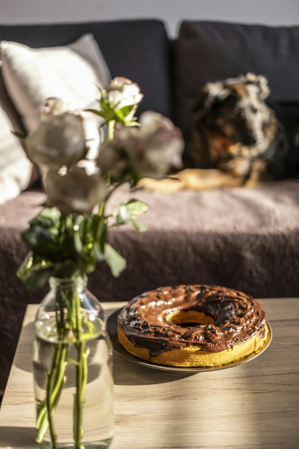 a table with a vase of flowers and a donut on it