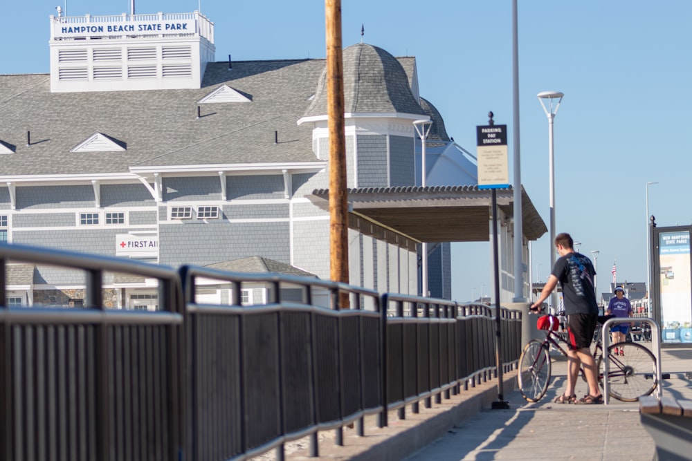 a man riding a bike down a sidewalk next to a tall building