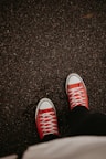 a person wearing red sneakers standing on a sidewalk