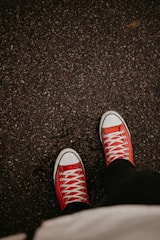 a person wearing red sneakers standing on a sidewalk